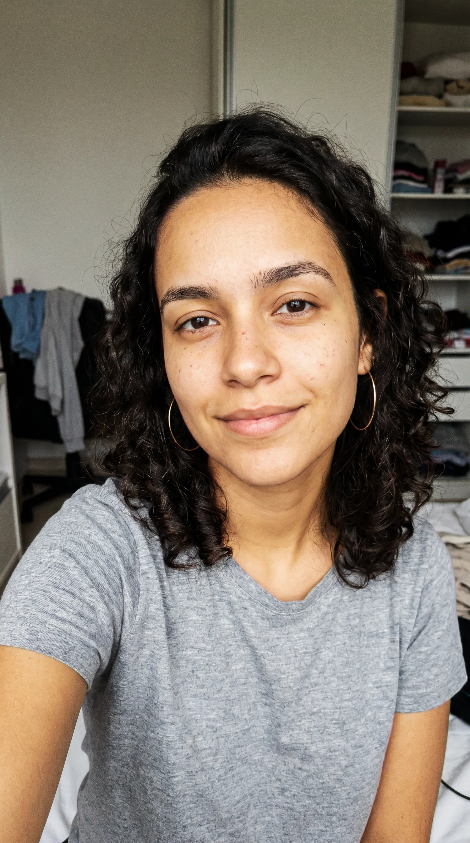 A imagem-âncora da influencer IA: mulher jovem de pele tan dourada, cabelo escuro cacheado, brinco de argola, olhando pra câmera. É o rosto-base.