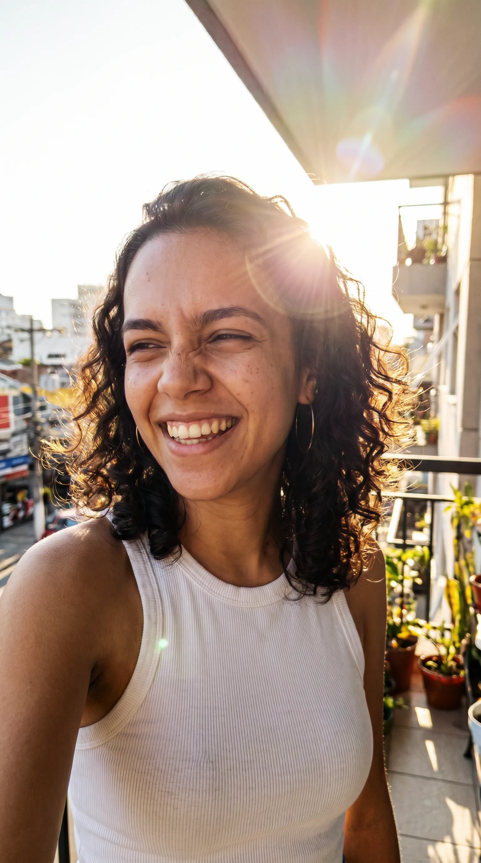 A mesma influencer num retrato de golden hour na varanda: contraluz quente, flare de sol, rindo de olhos apertados. Mesmíssimo rosto.